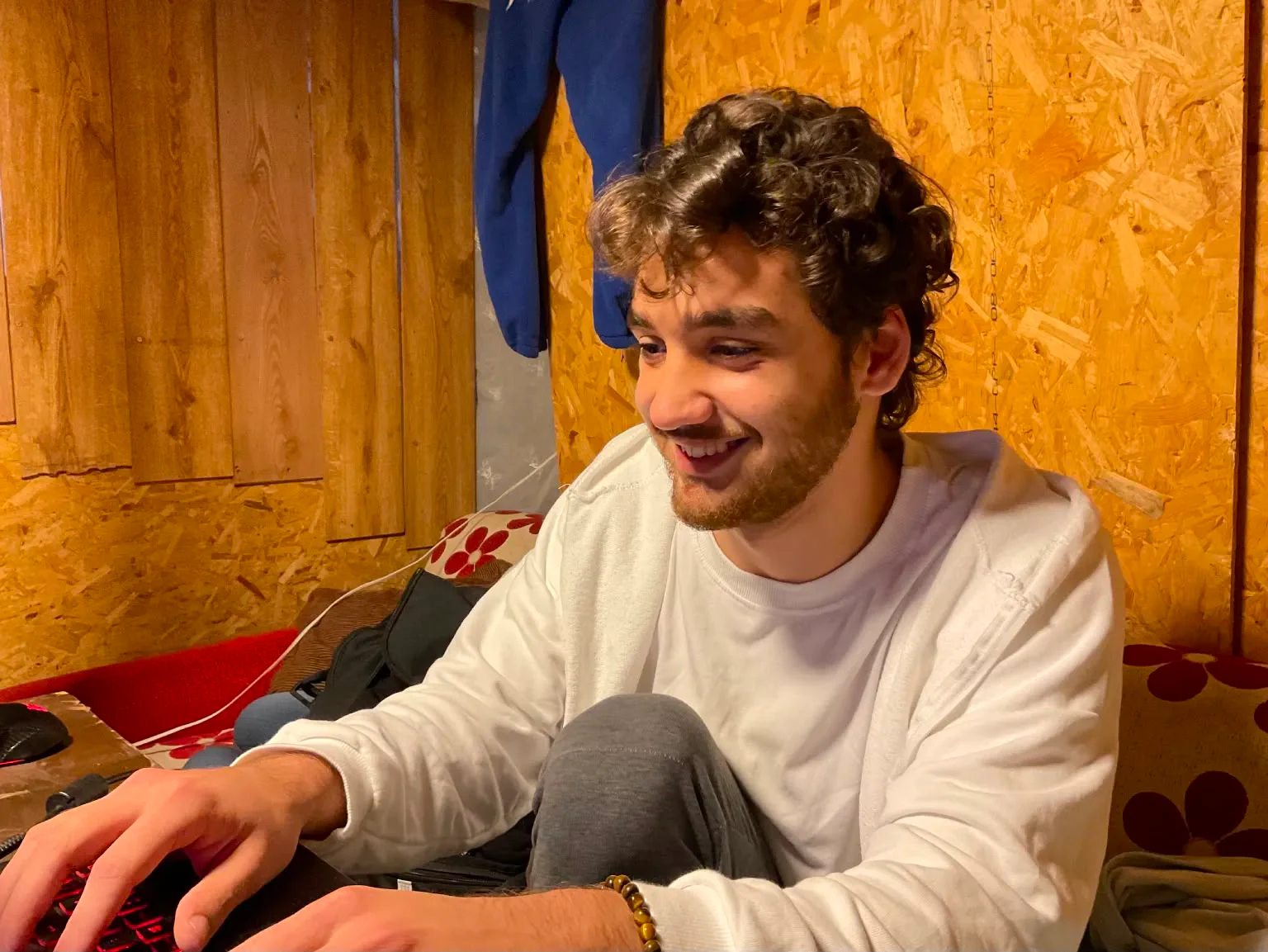 Alperen seated at a desk, smiling in a warm indoor setting.